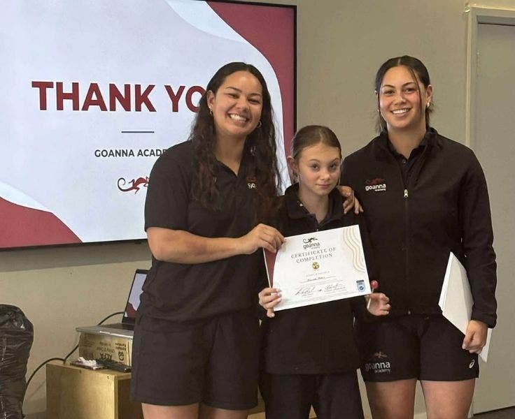 Photo of two mentor students happily celebrating a primary student holding a certificate.